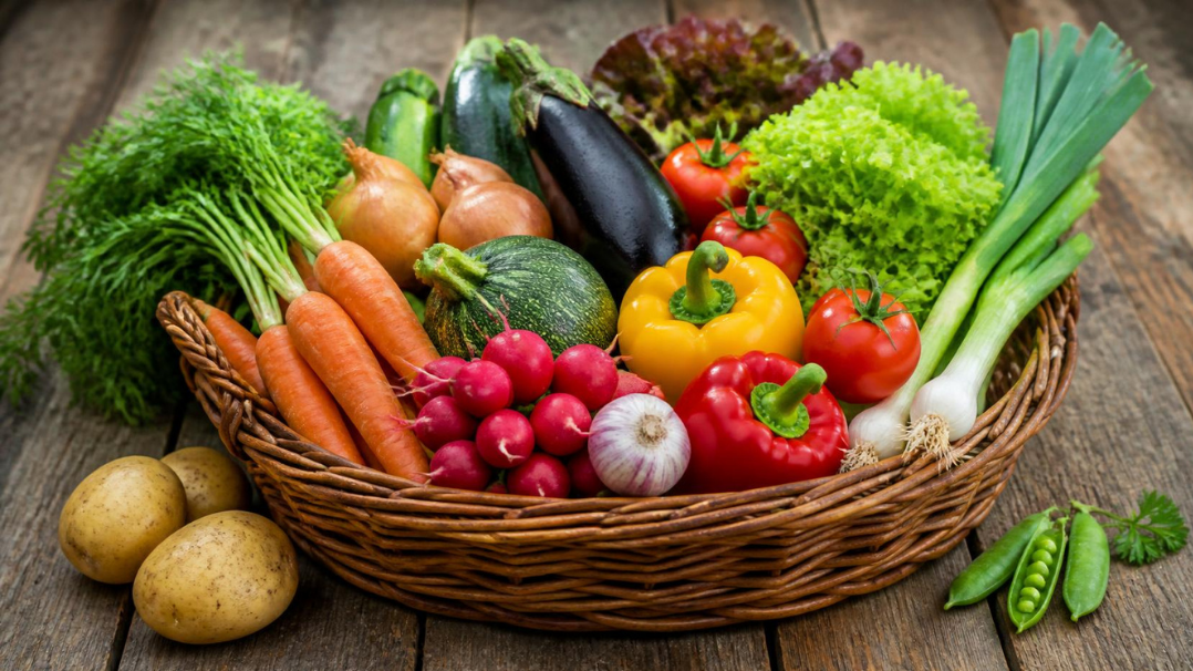 Panier de légumes de saison frais et colorés posé sur une table en bois